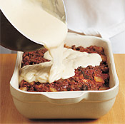 Pour warm b&eacute;chamel sauce over the moussaka, then use a spatula to smooth the top of the sauce.